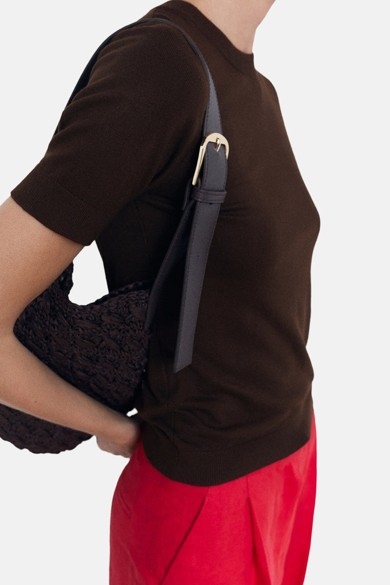 T-shirt à manches courtes brun de MANGO, porté avec un pantalon rouge et un sac tressé.