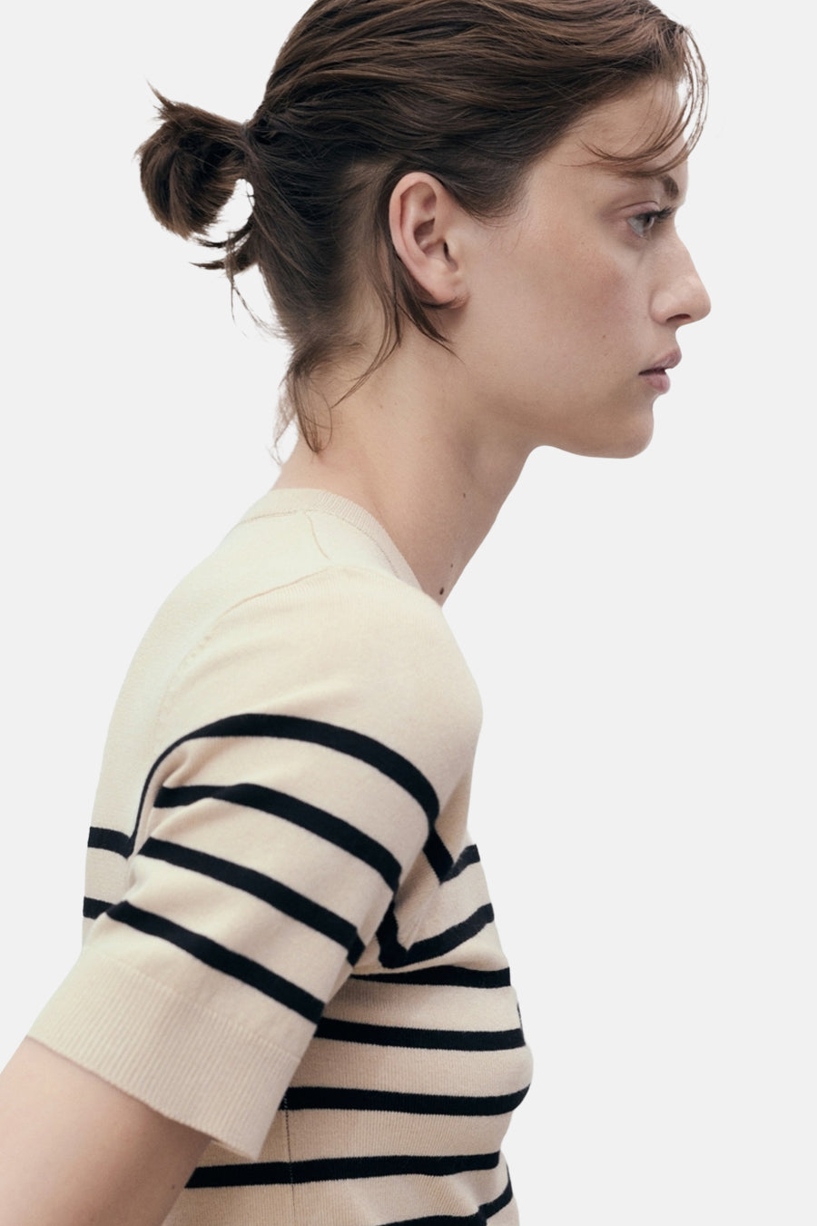 Beige T-shirt met zwarte strepen van MANGO, gedragen door een model van opzij gezien.