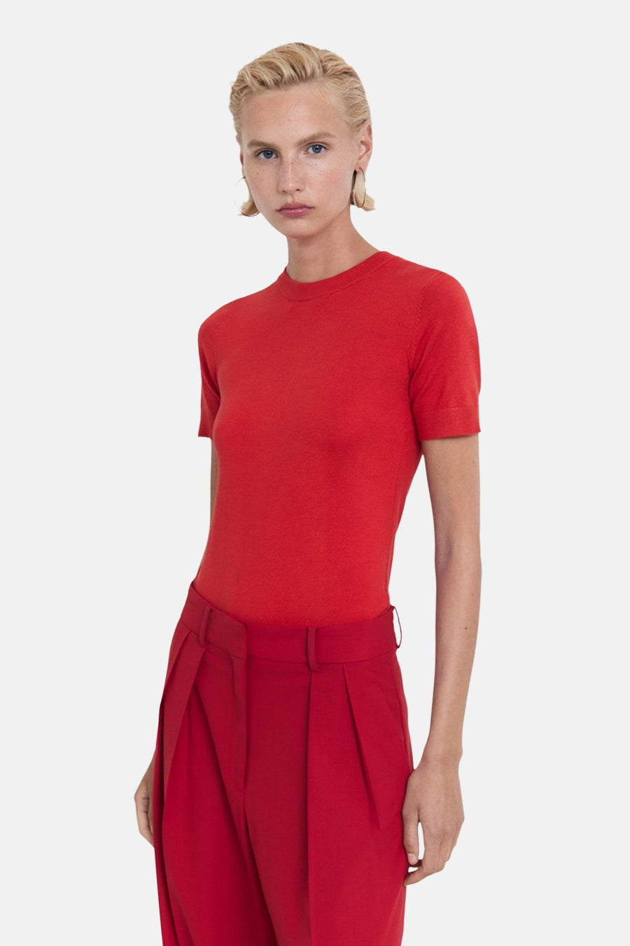 Rood T-shirt met korte mouwen van MANGO, gedragen met een bijpassende broek, op een effen achtergrond.