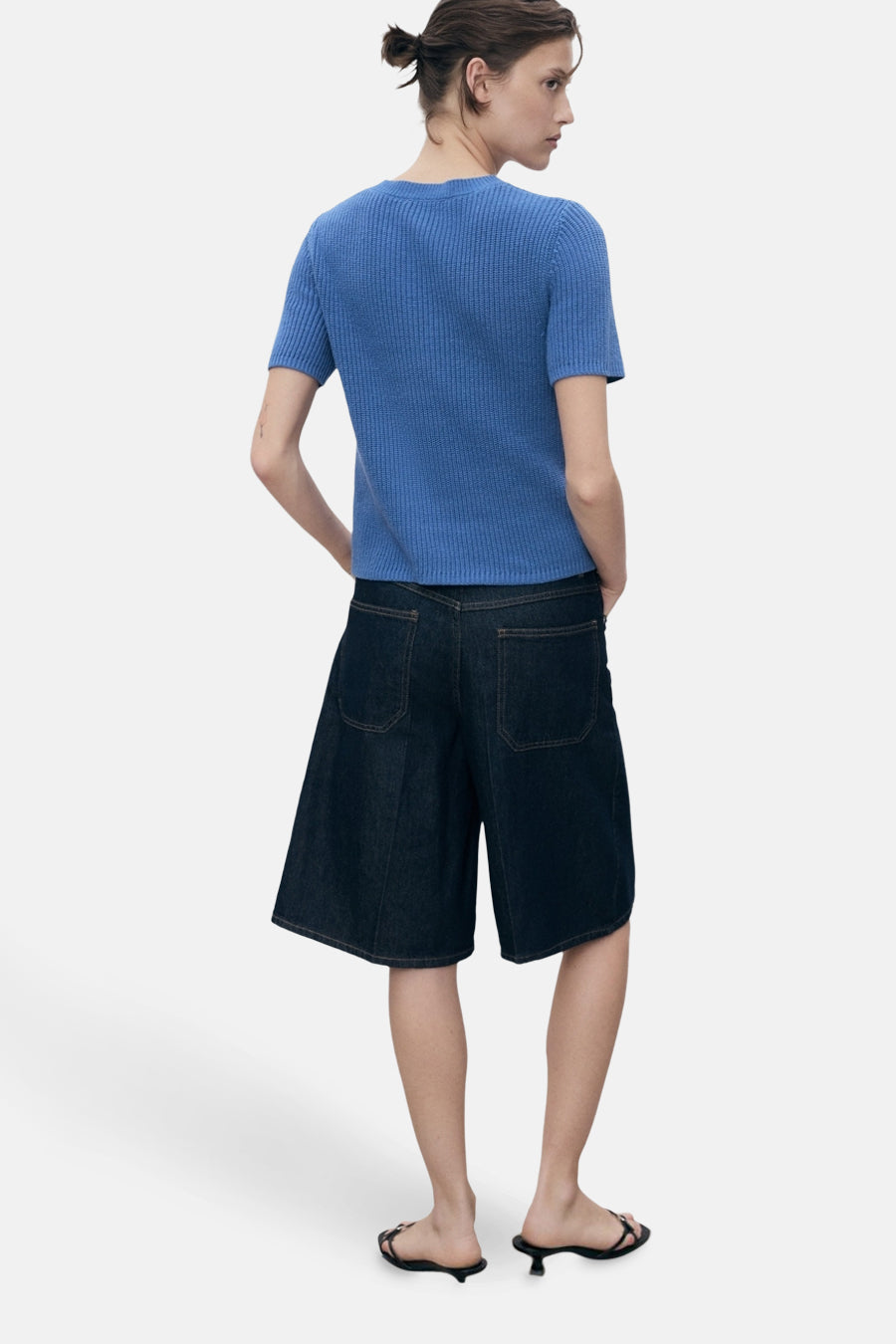 Blauwe MANGO-cardigan, in ribgebreide stof, gedragen met een wijde spijkerbroekshort en sandalen met hak.