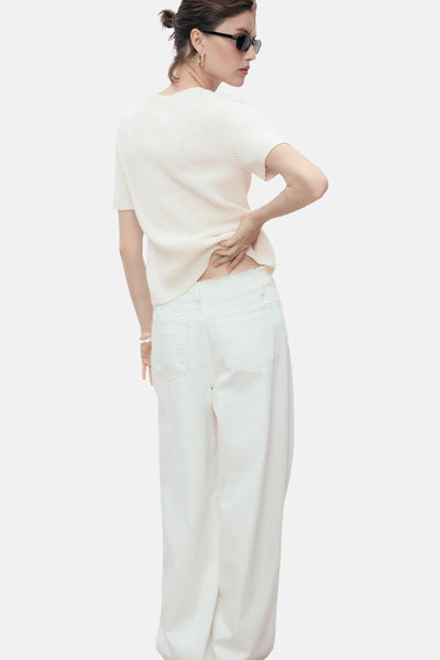 Witte gebreide cardigan van MANGO, gedragen met een witte broek met hoge taille, achterzicht.