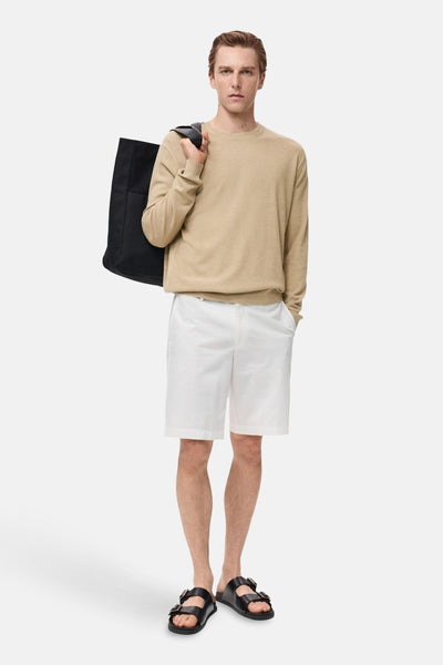 Beige ronde hals trui van MANGO, gedragen met een witte korte broek en zwarte sandalen, met een zwarte tas over de schouder.