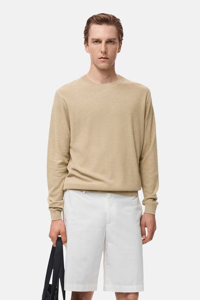 Beige ronde hals trui van MANGO, gedragen met een witte korte broek en een zwarte schoudertas.
