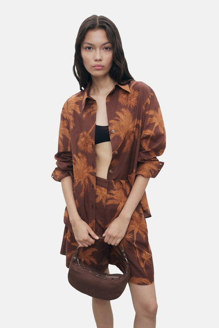 Bruin overhemd met lange mouwen van MANGO, met palmboomprint, open gedragen over een zwarte beha.