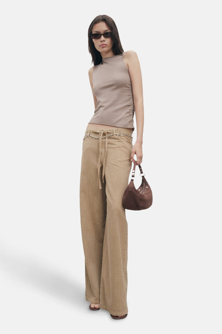 Top sans manches beige de MANGO, porté avec un pantalon taille basse et un sac marron.