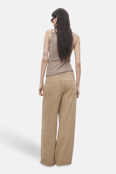 Top sans manches beige de MANGO, porté avec un pantalon large et des lunettes de soleil.