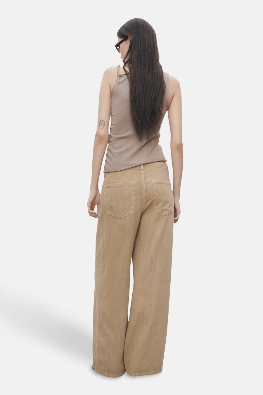 Top sans manches beige de MANGO, porté avec un pantalon large et des lunettes de soleil.
