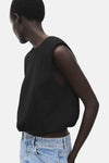 Top noir sans manches de MANGO, porté avec un jean taille haute bleu clair.
