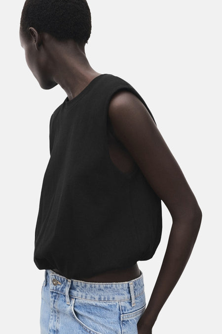 Zwarte mouwloze top van MANGO, gedragen met een lichtblauwe high-waist jeans.
