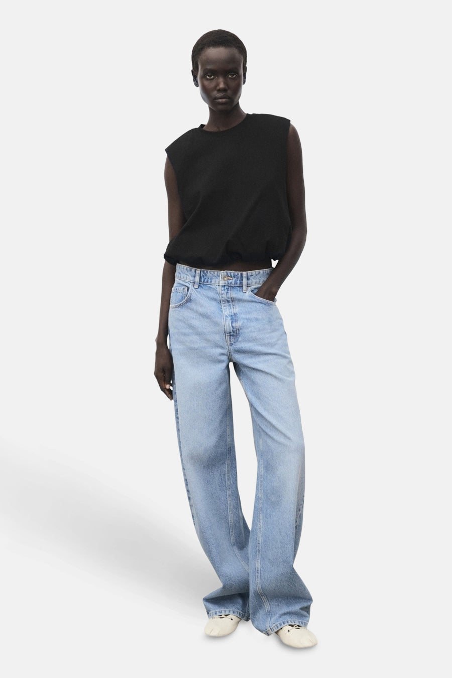 Top sans manches noir de MANGO, porté avec un jean ample bleu clair et des chaussures crème.
