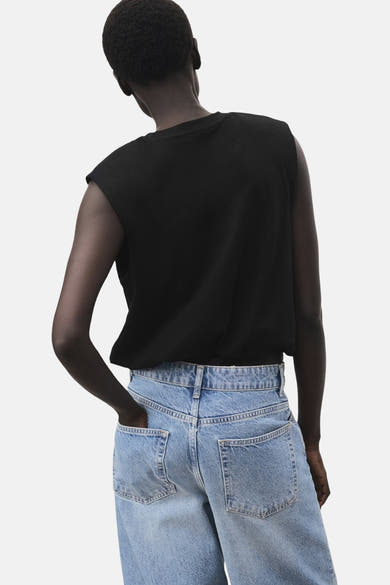 Top sans manches noir de MANGO, porté avec un jean taille haute bleu clair, vue de dos.
