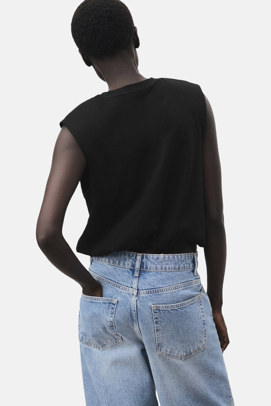 Top sans manches noir de MANGO, porté avec un jean taille haute bleu clair, vue de dos.
