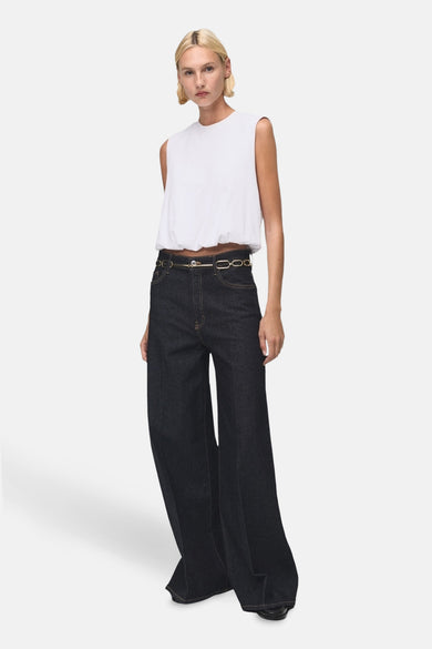 Top blanc sans manches de MANGO, porté avec un jean large taille haute et une ceinture dorée.