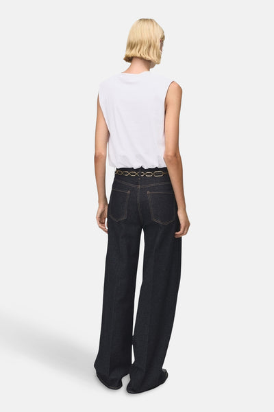 Débardeur blanc de MANGO, porté avec une ceinture dorée et un jean ample bleu foncé.