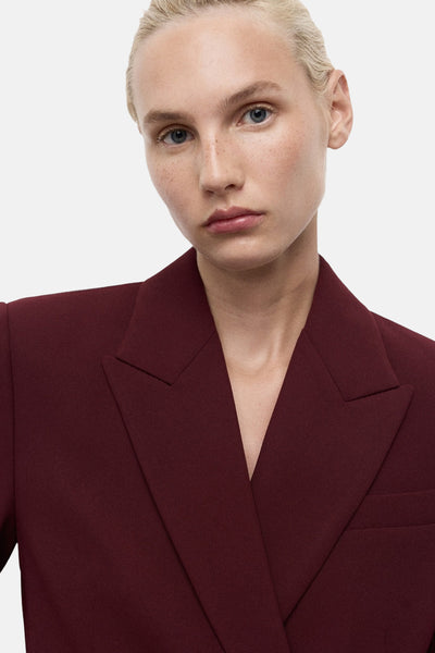 Bordeaux blazer van MANGO, dubbele rij knopen met inkepingen, gedragen door een mannequin met een lichte huidskleur.