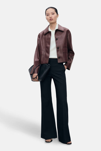 Veste courte bordeaux de MANGO, avec un pantalon noir évasé et un sac à main noir.