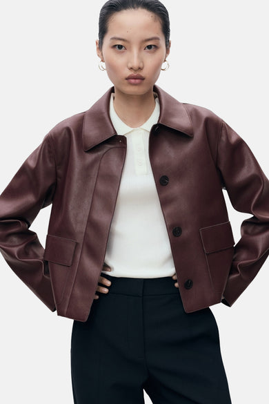 Veste courte bordeaux de MANGO, avec col tailleur, portée sur un polo blanc et un pantalon noir.