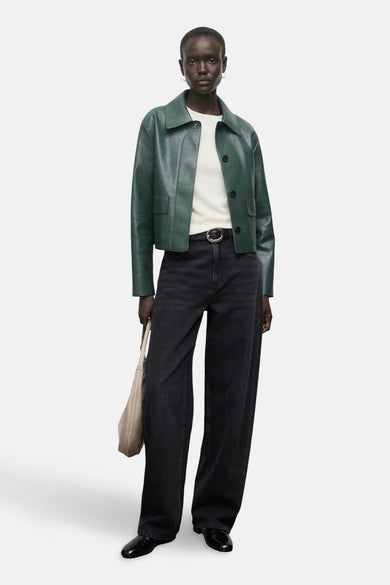 Veste courte verte de MANGO, avec col à revers, poches plaquées et fermeture boutonnée sur mannequin portant un jean ample.
