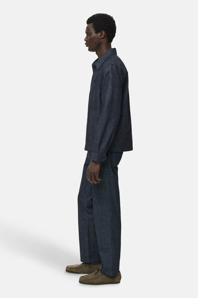 Veste en jean bleu foncé de MANGO, avec col et poche poitrine, portée avec un pantalon assorti et des chaussures marron.