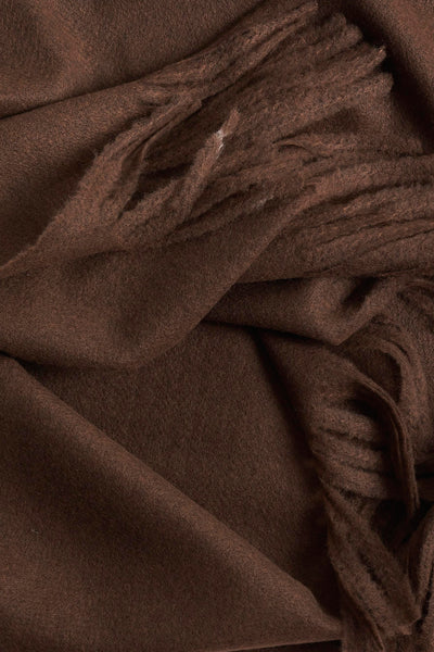 Écharpe marron, en textile doux de MANGO, avec une texture légèrement duveteuse et des franges apparentes.
