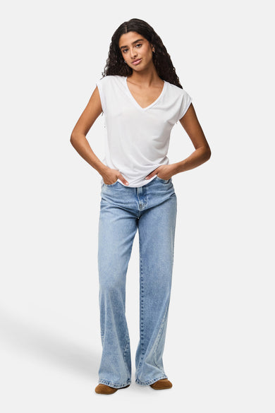 T-shirt blanc à col en V de PIECES, porté avec un jean taille haute ample et des chaussures marron.