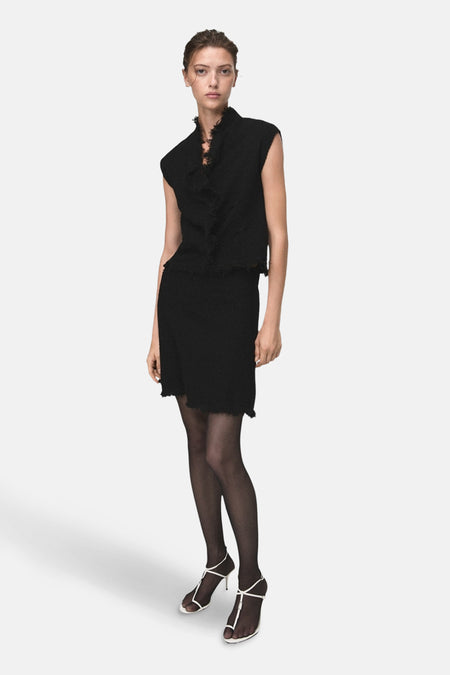 Zwart hemdje van MANGO, met V-hals en textuurdetail, gedragen met een zwarte broek en bruine pumps.