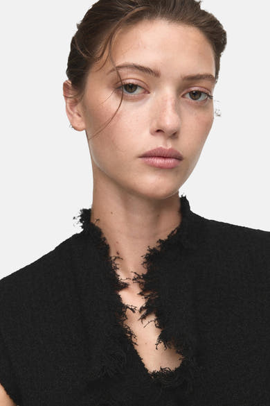Débardeur noir van MANGO, met een gerafelde halslijn, close-up.
