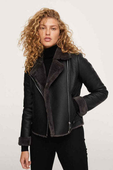Black leather biker jacket with shearling collar and cuffs, front zipper, worn over black turtleneck, front view
