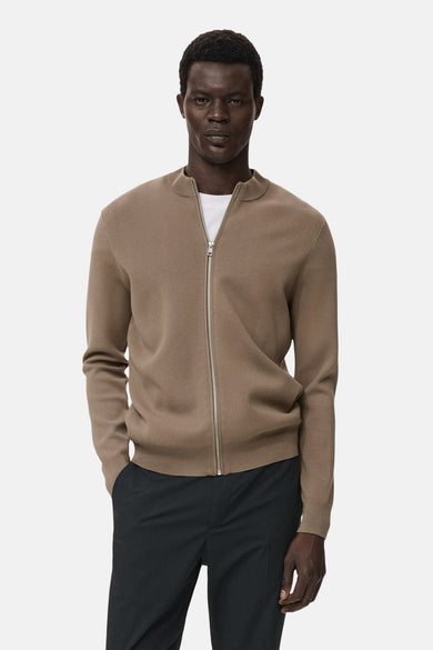 Bruin gilet van MANGO, gedragen over een wit T-shirt en een donkere broek, met een zilveren ritssluiting.