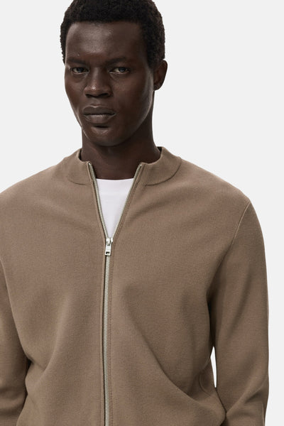 Bruin gilet van MANGO, met zilveren ritssluiting en ronde hals, gedragen over een wit T-shirt.