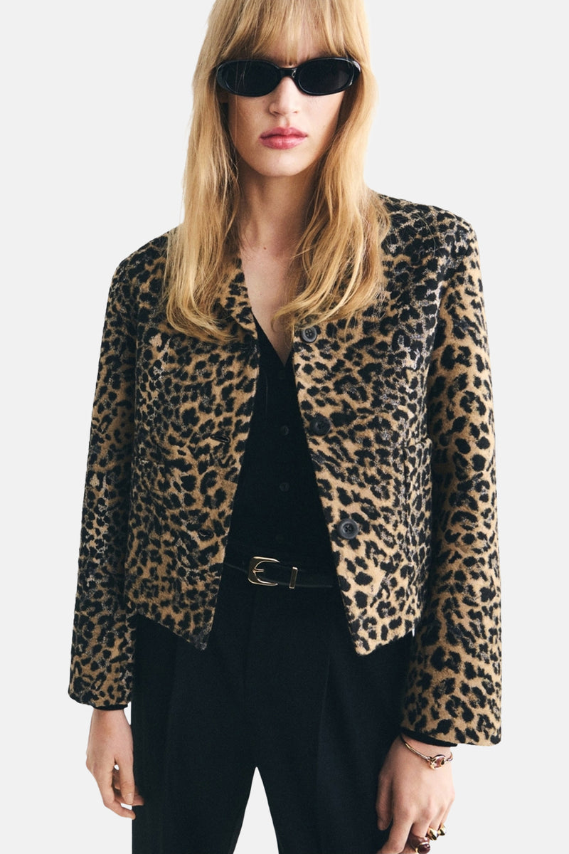 Blazer marron à motif léopard par MANGO, porté avec une chemise et un pantalon noirs, et des lunettes de soleil.