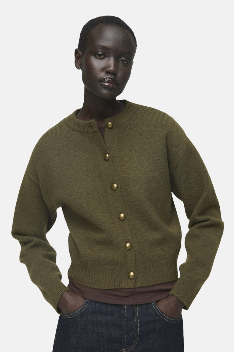 Kaki gilet van MANGO, gedragen met een bruin T-shirt en een donkere wijde broek, van achteren gezien.