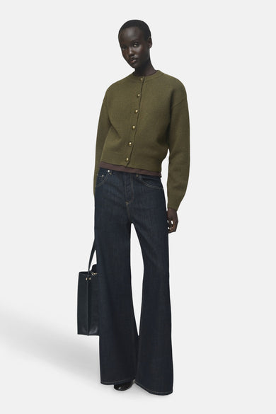 Gilet kaki de MANGO, porté avec un jean évasé et un sac à main noir.