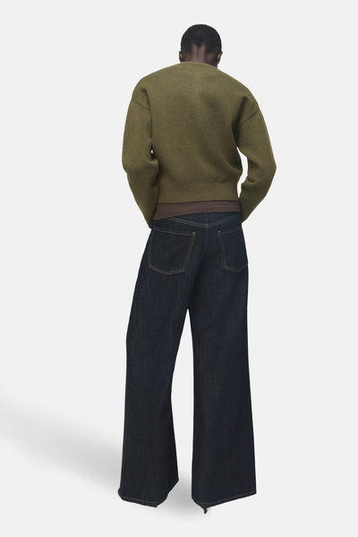 Gilet kaki de MANGO, porté avec un t-shirt marron et un jean foncé à jambes larges, vue de dos.