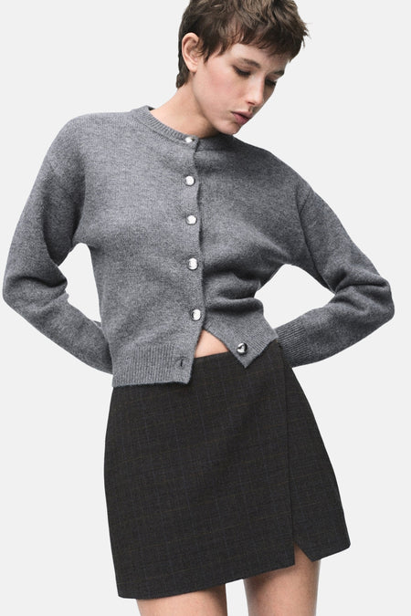 Grijze bodywarmer van MANGO, gedragen met een zwarte rok en grijze sokken, van achteren gezien.