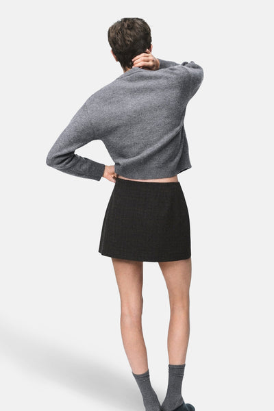 Gilet gris par MANGO, porté avec une jupe noire et des chaussettes grises, vue de dos.