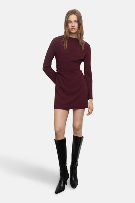 Robe bordeaux à manches longues de MANGO, portée avec des bottes noires montantes.