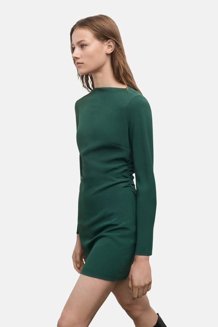 Groene jurk met lange mouwen van MANGO, gedragen met hoge zwarte laarzen met hak.