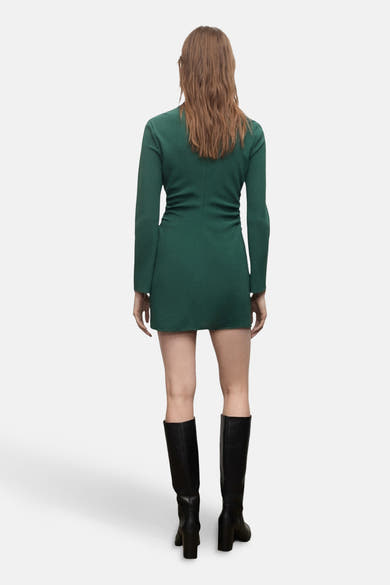 Robe verte à manches longues de MANGO, portée avec des bottes hautes noires à talons.