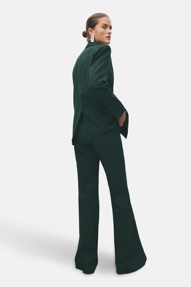 Pantalon vert de MANGO, coupe évasée et taille haute, porté avec un blazer assorti.