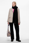 Zwarte sjaal van PIECES®, gedragen met een beige blazer, een roze trui en een zwarte broek.