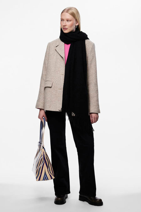 Zwarte sjaal van PIECES®, met franjes, gedragen met een beige blazer, een zwarte broek en een gestreepte tas.