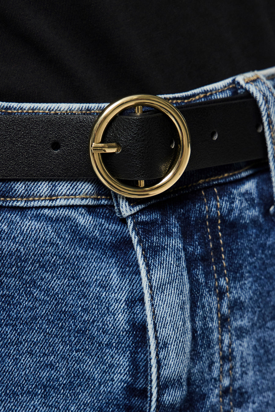 Zwarte PIECES® riem met gouden gesp, gedragen met een lichtblauwe jeans en een zwart T-shirt.