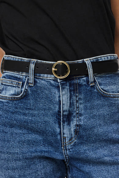 Zwarte PIECES® riem met gouden gesp gedragen met een lichtblauwe spijkerbroek.