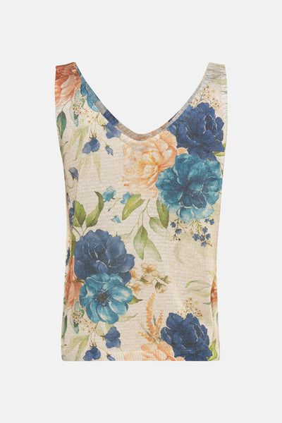 Débardeur bleu de Terra di Siena avec motif floral bleu et pêche sur un tissu texturé beige.