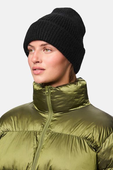 Bonnet noir de PIECES®, porté avec une doudoune vert olive et un col montant.