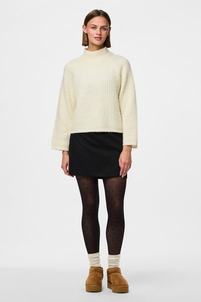 Zwarte stippenpanty van Pieces, gedragen met een minirok en camelkleurige enkellaarsjes.