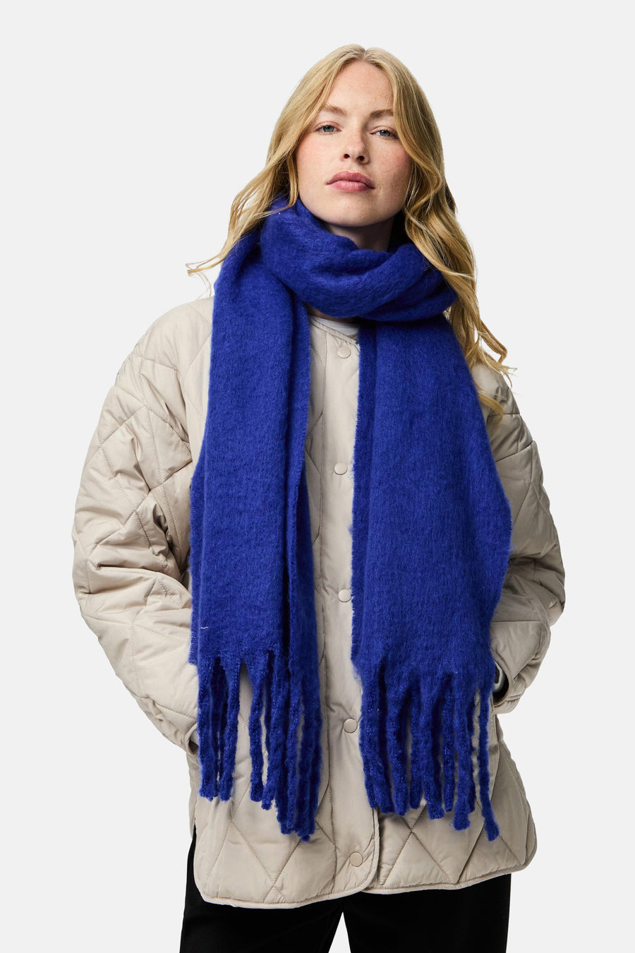 Écharpe bleu de PIECES® avec des franges texturées portée avec une veste matelassée beige.
