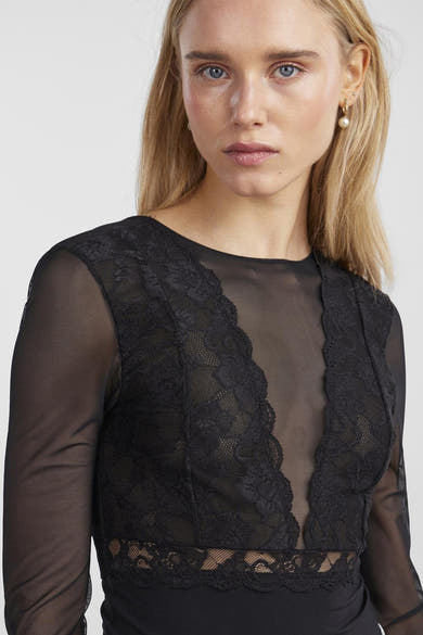 Body noir en dentelle de PIECES®, avec manches longues transparentes et détail de bijoux dorés.