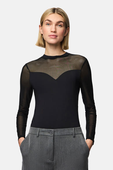 Body noir de PIECES®, avec des manches longues en tulle transparent et porté avec un pantalon gris à taille haute.